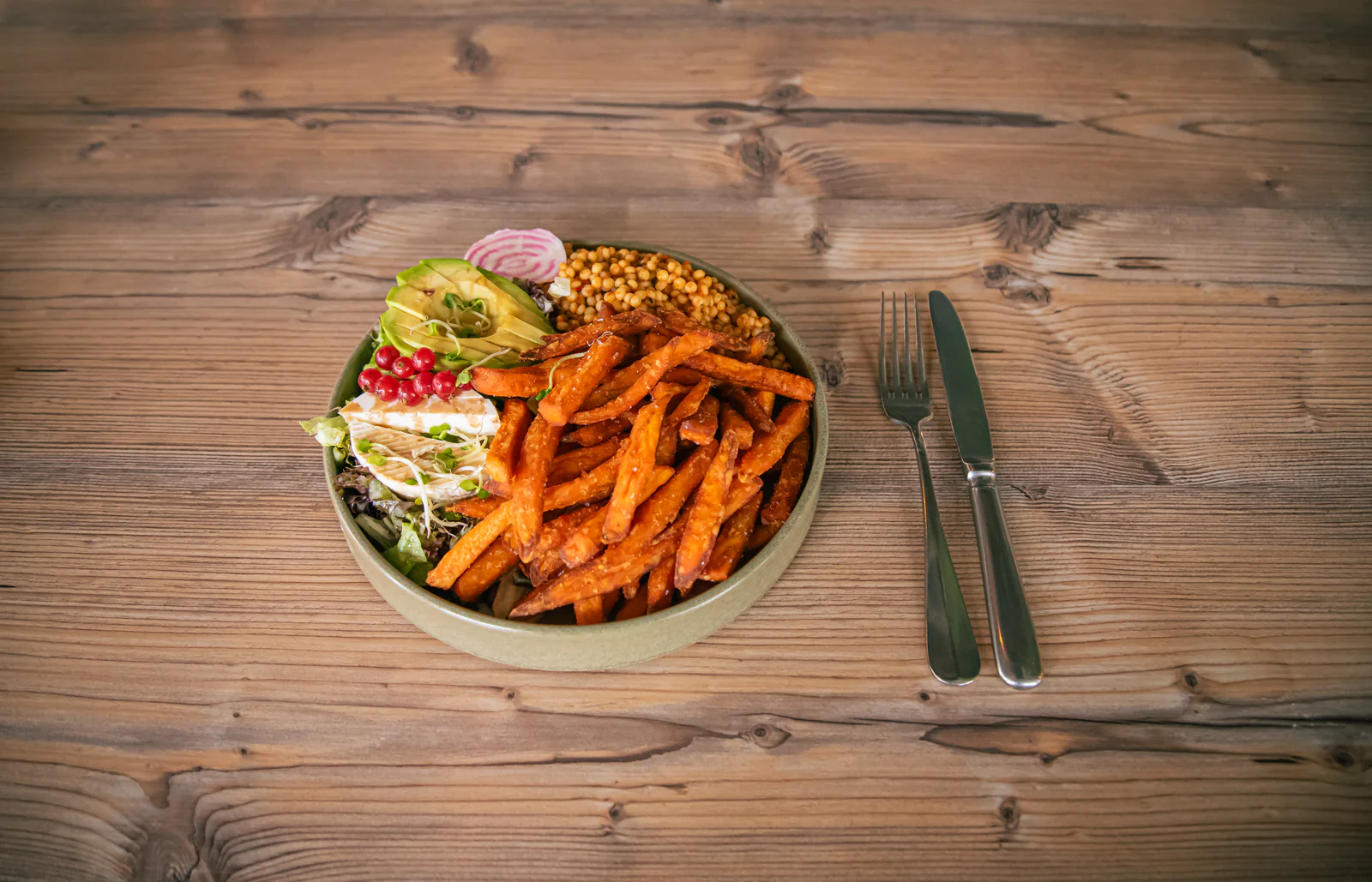 Bowl mit Süßkartoffel-Pommes, Avocado, Salat und Käse.